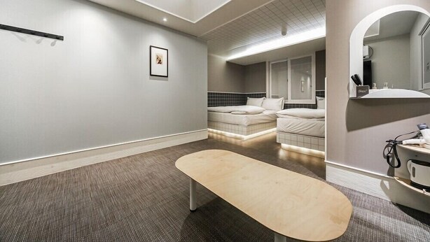 A modern bathroom with a bench, a large mirror, and a shower area.