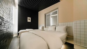 A hotel room with a brick wall, a black ceiling, and a large window.
