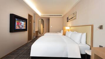 A hotel room with a large bed, a television mounted on the wall, and a mirror.