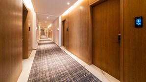 A hotel hallway with wooden doors, a patterned carpet, and recessed lighting. - Xence Hotel (Xiamen)