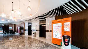 A hotel lobby with a marble floor, a reception desk, a vending machine, and a digital information kiosk. - Xence Hotel (Xiamen)