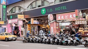 A T.O. Hotel with multiple signs in a foreign language, a row of parked scooters, and a busy street scene. - T.O Hotel Main Station (Taipei)