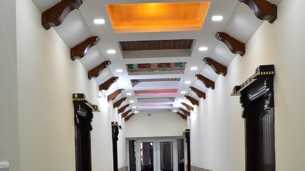 A hallway with patterned tile flooring, wooden columns, and a ceiling with recessed lighting. - Dream Land Hotel (Murree)