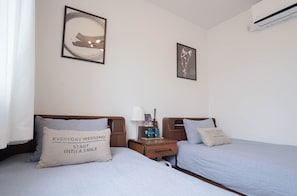 A hotel room with two beds, a nightstand with a lamp, and framed artwork on the walls. - ZAITO Tokyo Kinshicho Economy Inn (Tokyo)