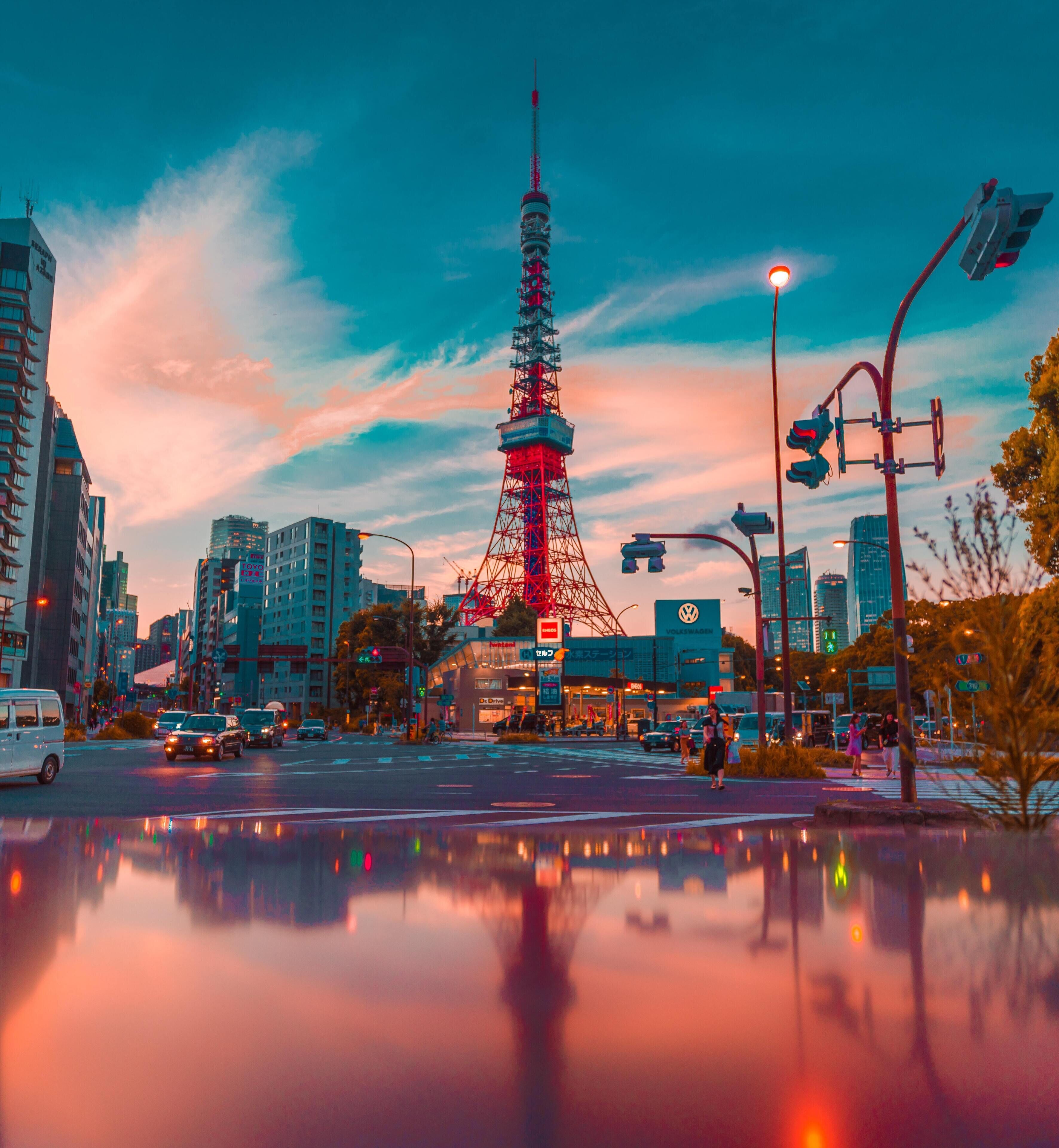 A cityscape with a prominent tower, likely a landmark, surrounded by modern buildings and a reflective water surface.