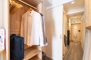 A hotel room with a wooden wardrobe, a hanging coat rack, a suitcase, and a laundry machine. - ZAITO Tokyo Kinshicho Economy Inn (Tokyo)