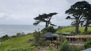 Une propriété située sur la côte, offrant une vue sur la mer, dotée d’un espace extérieur couvert et d’une pelouse.