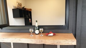 Un comptoir de bar en bois, avec deux verres de vin blanc, une bouteille de champagne et une assiette de fraises.