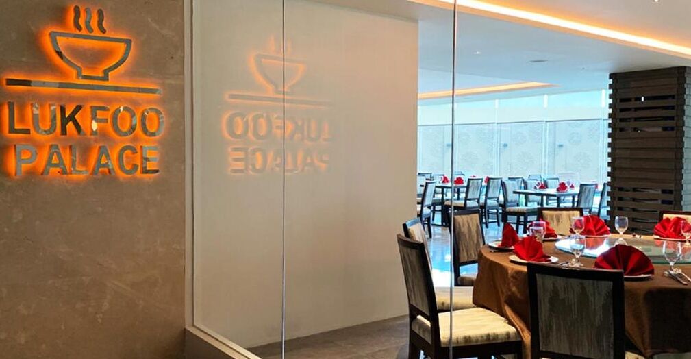 A restaurant with a modern interior, including a dining area with tables set for service and a visible logo on the wall.