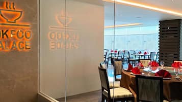 A restaurant with a modern interior, including a dining area with tables set for service and a visible logo on the wall.