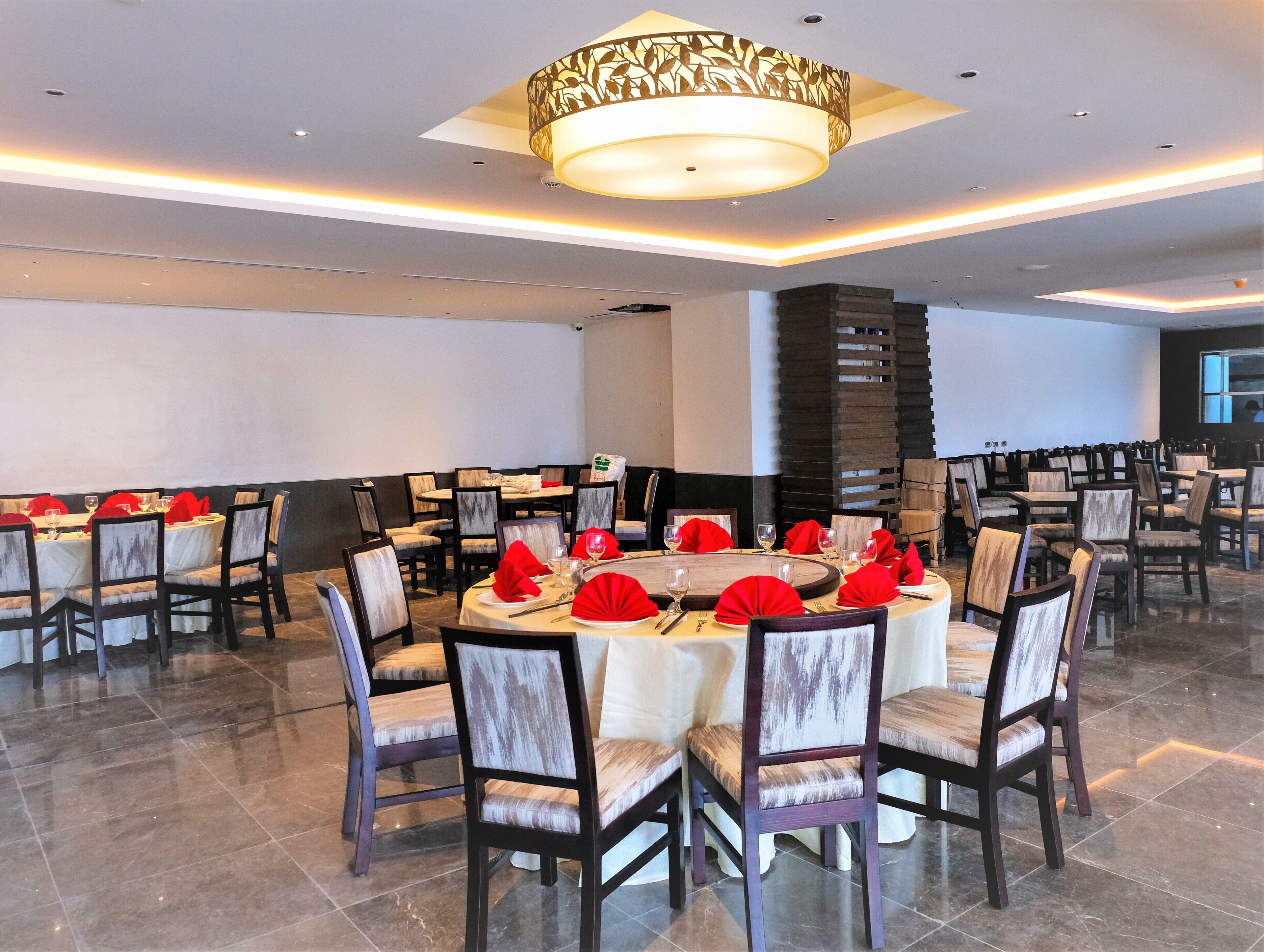 A conference room with round tables, chairs, and red napkins.