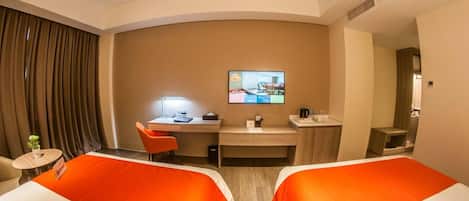 A hotel room with two beds, a desk, a TV, and a small table with a plant.