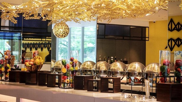 A modern hotel lobby with a central reception desk, a decorative ceiling, and a view of the outdoors through large windows. - Acacia Hotel Davao (Davao)