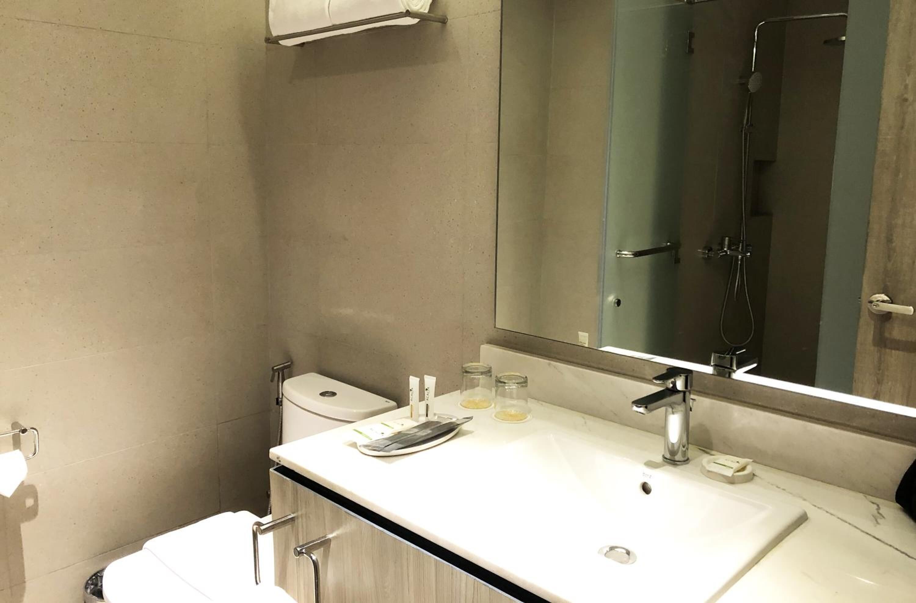 A modern bathroom with a white sink, a large mirror, and a shower.