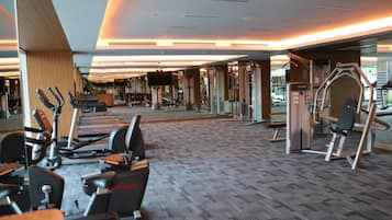 Un gimnasio con máquinas de cardio, bancos de pesas y espejos.