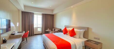 Habitación de hotel con cama, escritorio, silla, mesita y televisor.