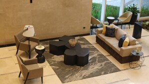 A modern lobby with a sofa, chairs, a lamp, and a coffee table. - Acacia Hotel Davao (Davao)
