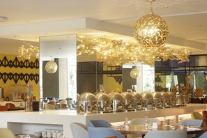 A modern dining area with a long counter, multiple dining tables, and a decorative ceiling light fixture. - Acacia Hotel Davao (Davao)