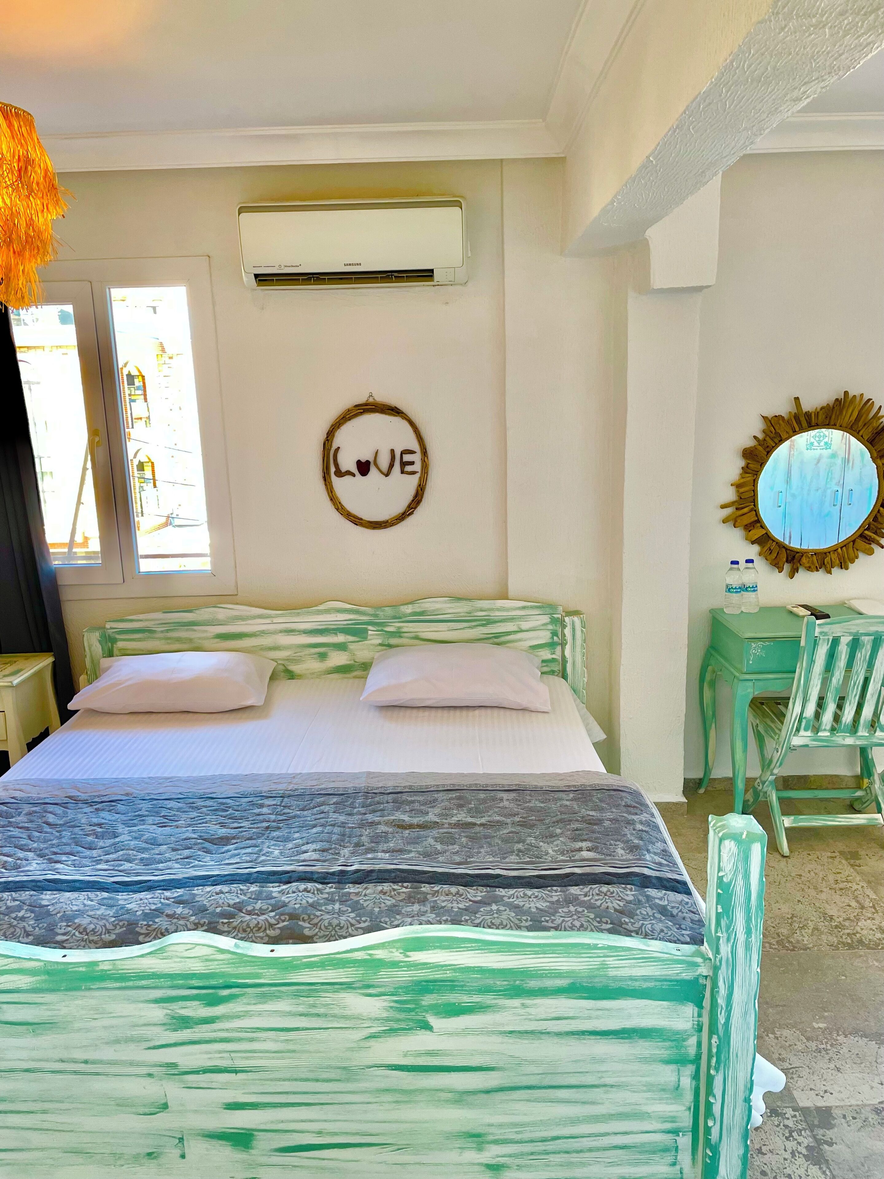 Un dormitorio con cama, aire acondicionado de pared, espejo y ventana.