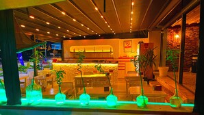 Un restaurant doté d’un bar, de plusieurs tables, de chaises et de plantes en pot.