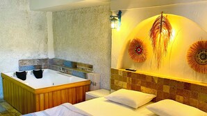 Une chambre à coucher avec un grand lit, une baignoire en bois et un luminaire décoratif fixé au mur.