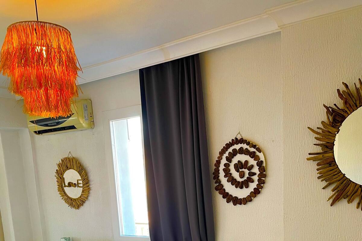 A bedroom with a bed, a nightstand, a wall decoration, and a ceiling light fixture.