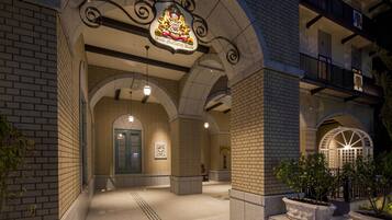 A building entrance with a prominent coat of arms sign, brick walls, and a well-lit interior.