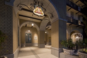 A building entrance with a prominent coat of arms sign, brick walls, and a well-lit interior. - Hotel Monterey KOBE (Kobe)