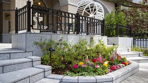 A stone staircase leading to a black metal fence with a flower garden in front. - Hotel Monterey KOBE (Kobe)