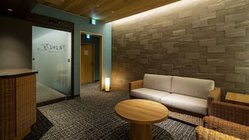 Eine Lobby mit einer Rezeption, einer Couch und einem runden Holztisch.