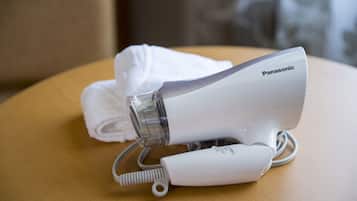 A Panasonic hair dryer on a wooden surface with a white towel beside it.