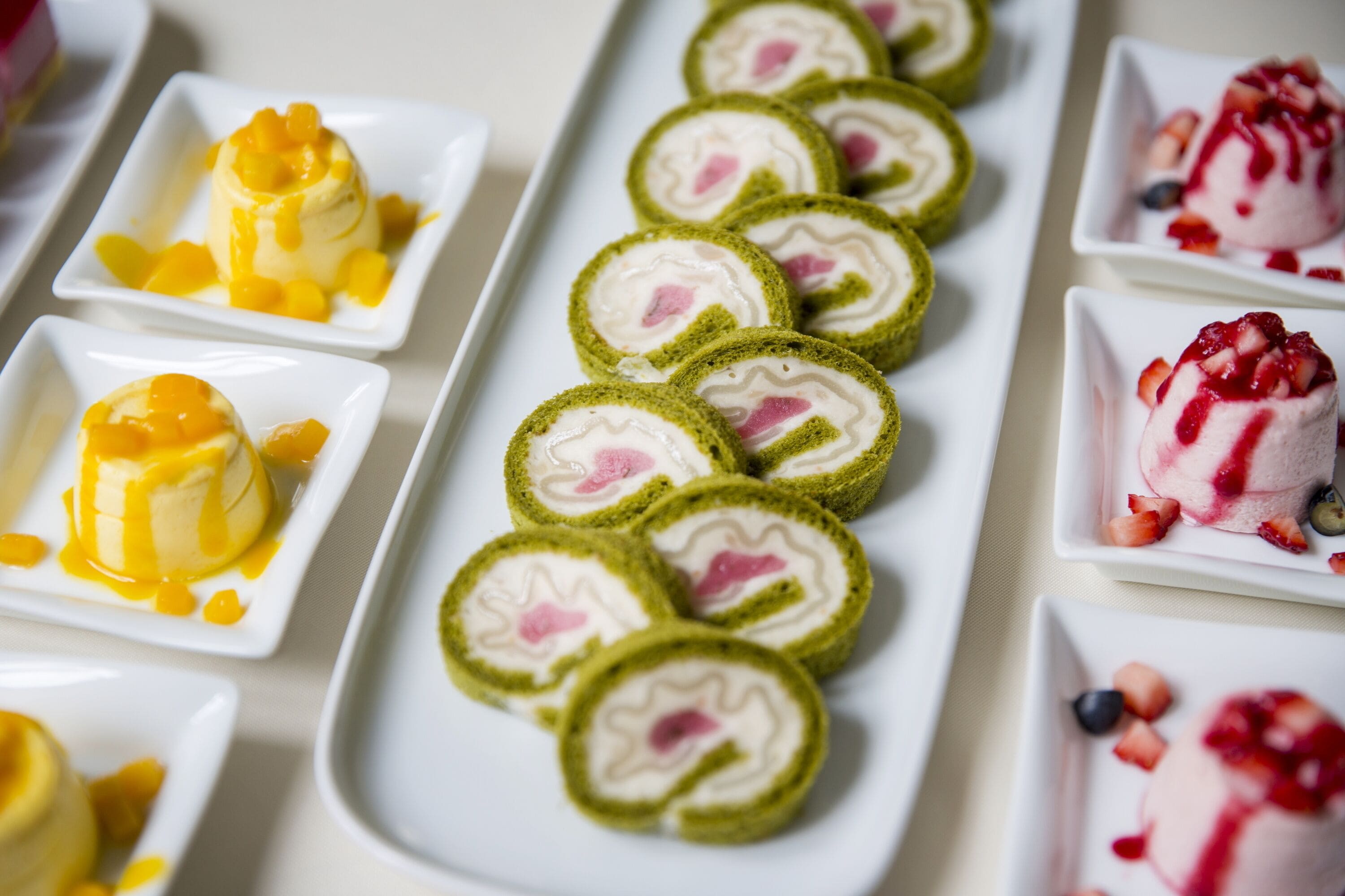 A variety of desserts on white square plates.