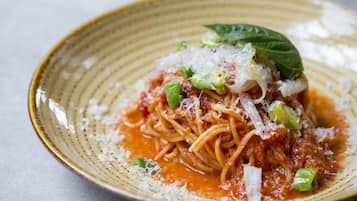 A plate of spaghetti with tomato sauce, grated cheese, and green onions.