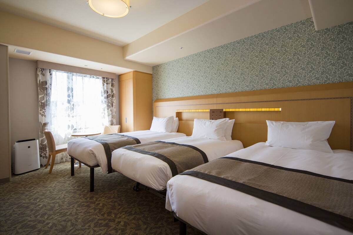 A hotel room with two beds, a desk, and a chair.