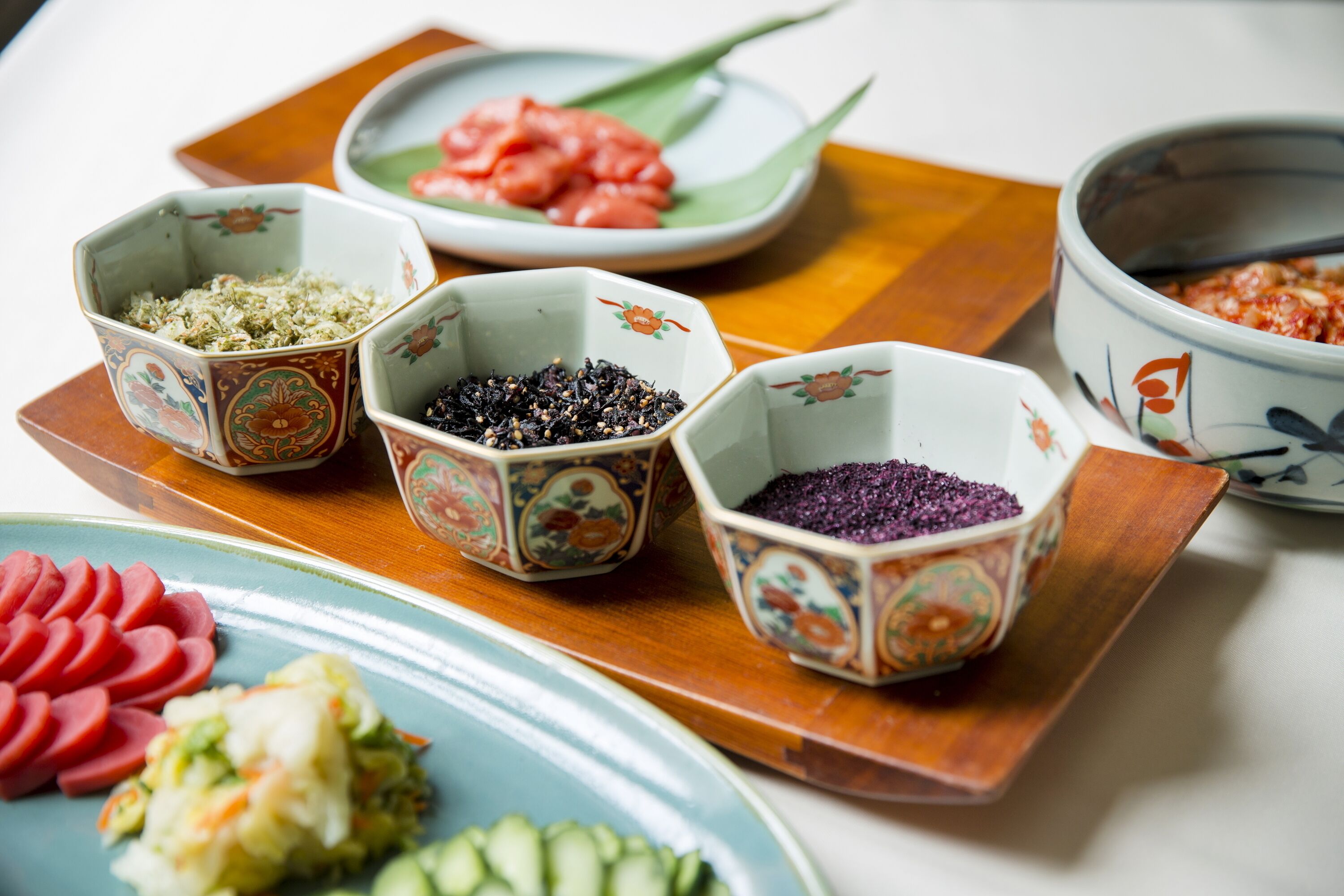 Una variedad de platos sobre una tabla de madera, incluyendo carne en rodajas, verduras y diferentes tipos de verduras encurtidas.