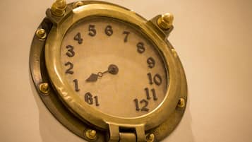 A brass clock with Roman numerals on a wall.