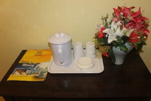 Un vassoio con una caffettiera, zucchero a cubetti e un brocchettino sul tavolo, accanto a una brochure e un vaso di fiori.