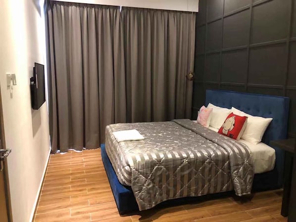 A bedroom with a bed, curtains, a TV, and a blue headboard. - Skyline (Phnom Penh)