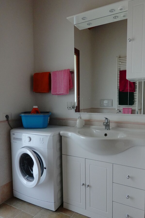 A compact bathroom with a washing machine, a sink, and a mirror. - Residences Gattopardu- "The Poet" (Castiadas)