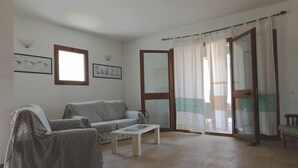 A living room with a sofa, a coffee table, a chair, a window, and a door leading to a balcony. - Residences Gattopardu- "Gone with the Wind" (Castiadas)