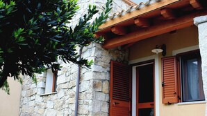 A stone building with a wooden door and shutters, a window, and a small balcony. - Residences Gattopardu- "Gone with the Wind" (Castiadas)