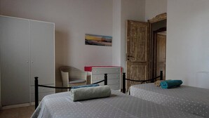 A bedroom with two beds, a wardrobe, a chair, a small table, and a painting on the wall. - Residences Gattopardu- "Gone with the Wind" (Castiadas)