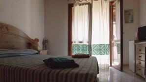 Une chambre à coucher avec un lit, une commode, un téléviseur et une vue sur l’extérieur.