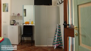 Une chambre à coucher de taille modeste, comprenant un placard, un petit bureau et un téléviseur.
