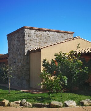 A traditional stone building with a modern extension, surrounded by a well-maintained lawn and large rocks. - Residences Gattopardu- "The Little Prince" (Castiadas)