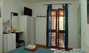 A bedroom with a bed, a desk, a mini fridge, and a TV. - Residences Gattopardu- "The Little Prince" (Castiadas)