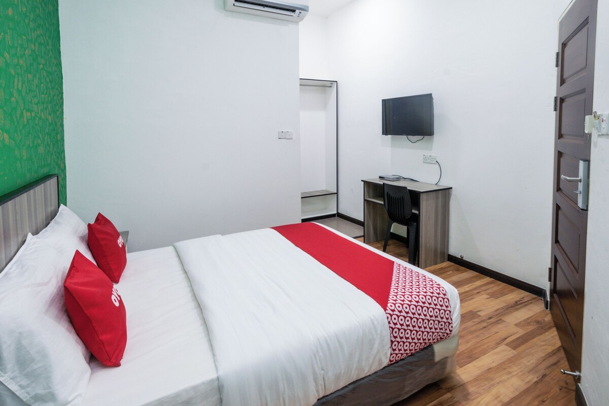 A hotel room with a bed, a desk, a chair, a flat-screen TV, and a wardrobe.