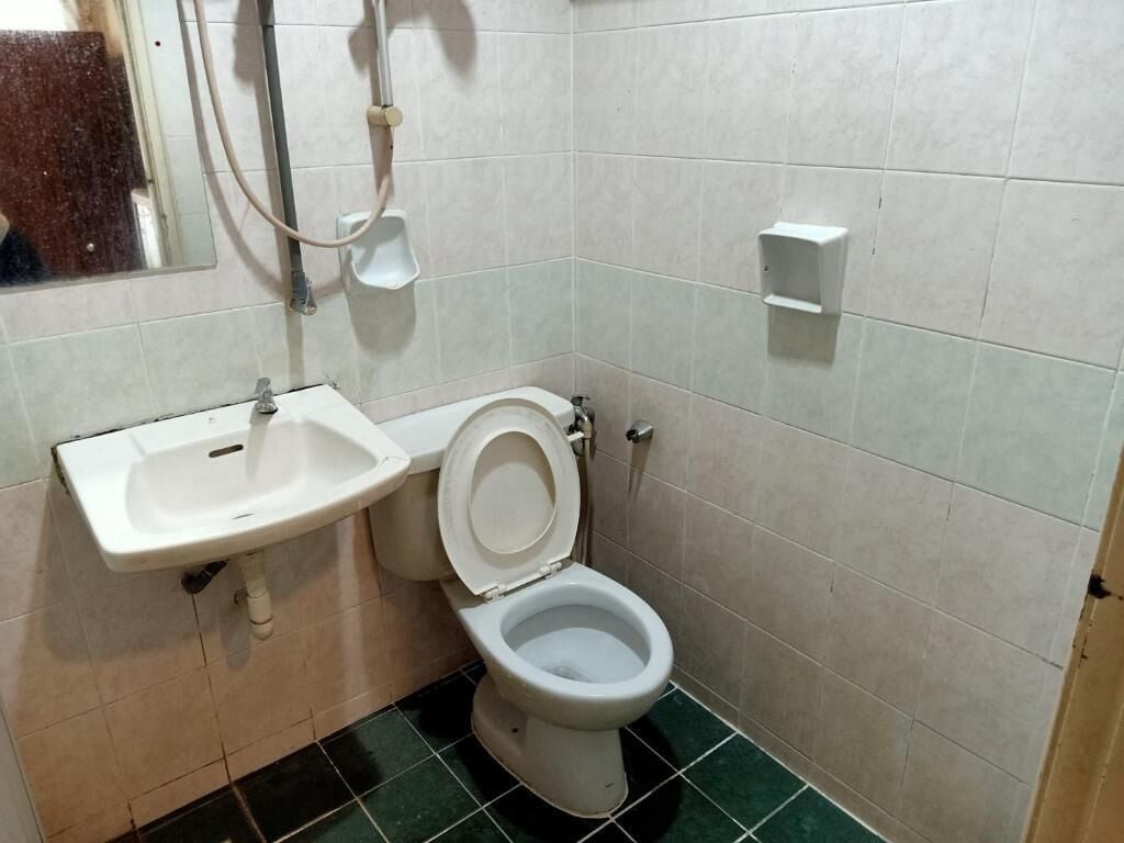 A bathroom with a toilet, sink, and a mirror.