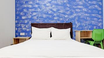 Una cama con ropa de cama blanca, cabecera marrón y pared con diseño azul.