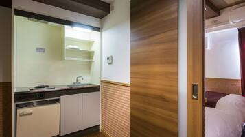 A compact kitchenette with a sink, stove, and storage cabinets.